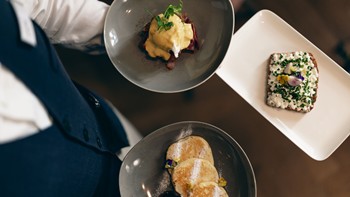 A waiter skillfully serves three beautiful dishes at the Veranda restaurant.