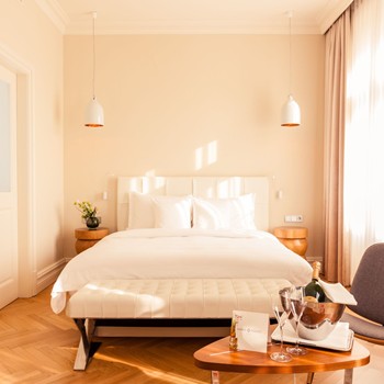 Helles Luxury Zimmer mit Doppelbett, Champagner auf dem Tisch und warmem Licht.